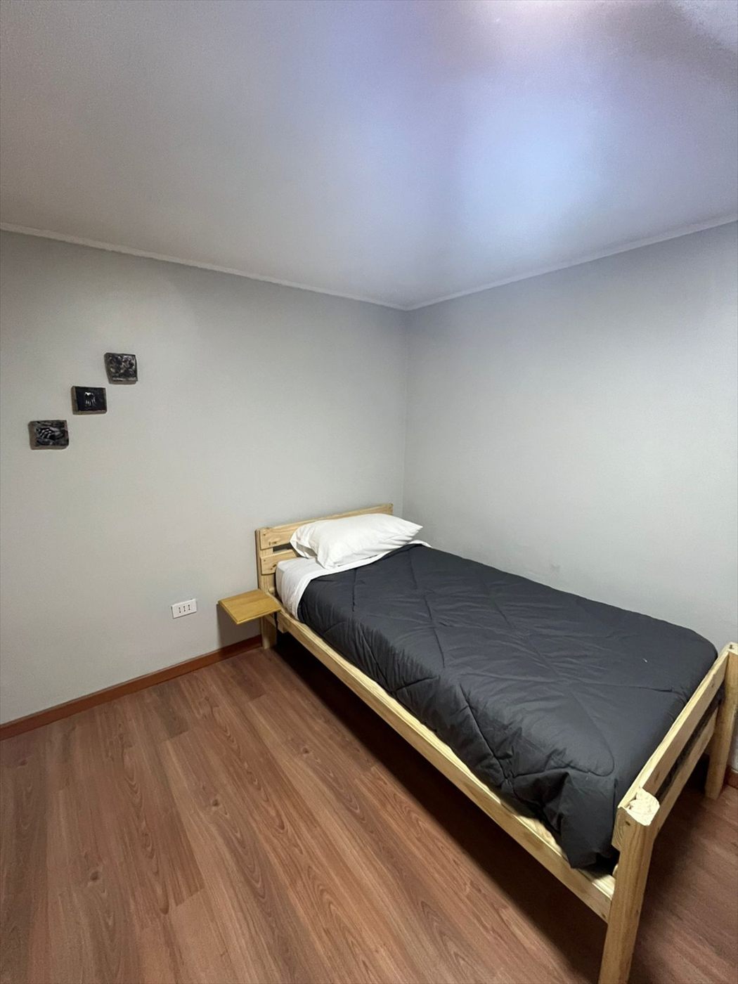 Habitación simple con cama individual y velador