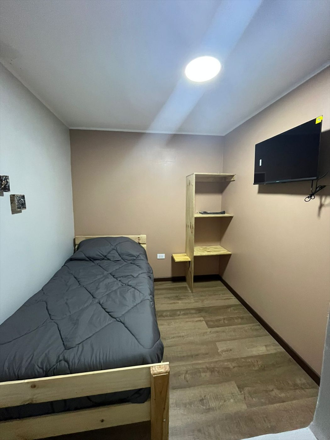 Habitación con televisor en el muro y repisa