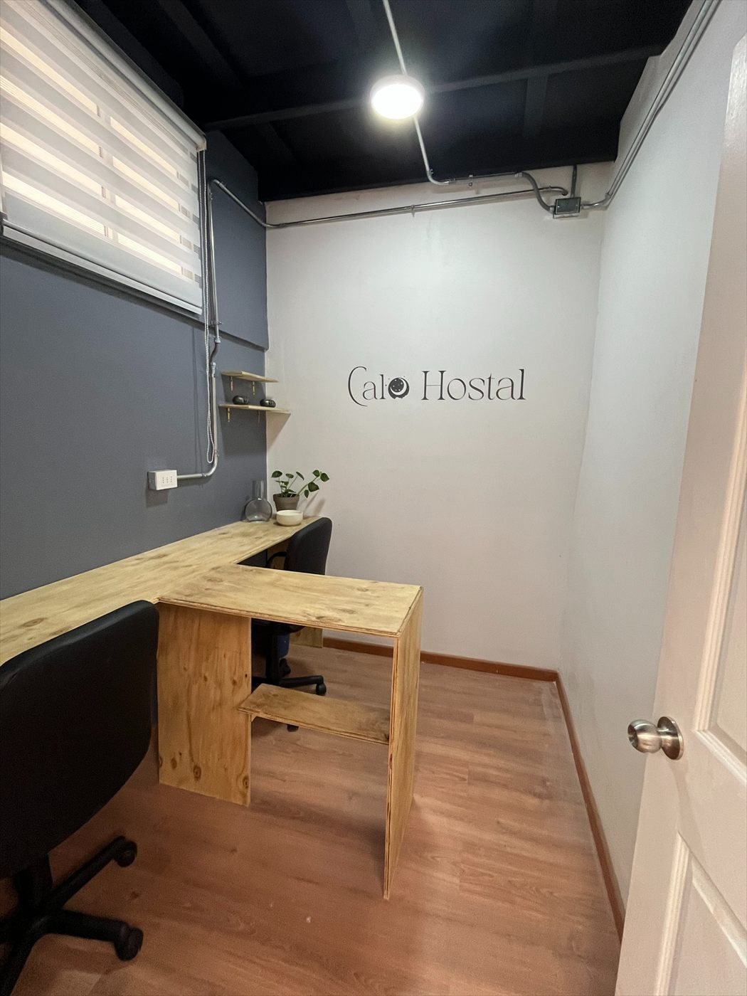 Escritorio de madera con el logo de Calo Hostal en el muro